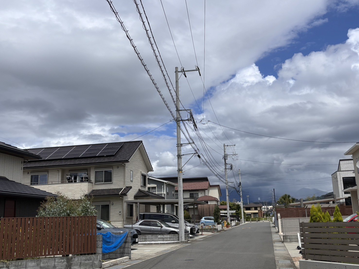 電柱のある住宅街の戸建て屋根に並ぶ太陽光パネル